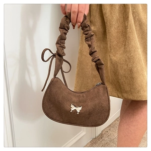 Detail of a brown suede half-moon bag with a silver butterfly buckle and ruched strap