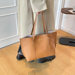 Detail of camel leather tote bag showing slim double handles and fashion branding