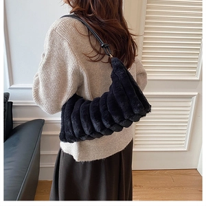 Detailed view of black plush handbag with horizontal pleats and thin leather strap