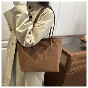Close-up of leopard print tote bag in brown suede fabric worn with a beige trench coat