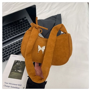 Detail view of brown suede underarm bag with silver butterfly buckle and bow strap