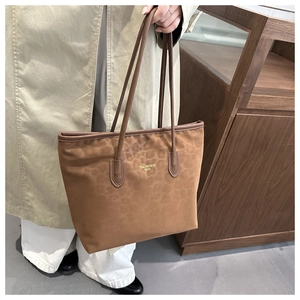 Close-up of leopard print tote bag featuring brown leather handles and gold logo branding