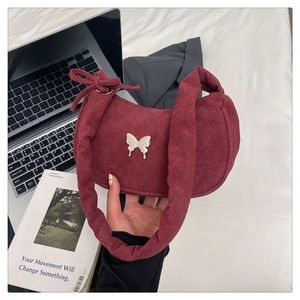 Detail of burgundy suede shoulder bag with silver butterfly buckle and pleated handle