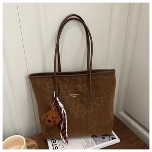 Detailed view of brown leopard-patterned tote bag with golden logo and teddy bear charm