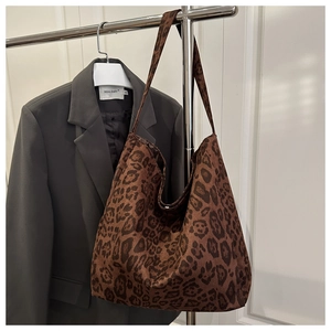 Close-up of brown leopard print suede tote bag with wide strap on a hanger