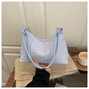 Gros plan du sac à bandoulière en velours bleu clair avec texture géométrique