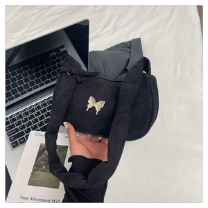 Detail of black suede hobo bag with a polished silver butterfly metal emblem ornament