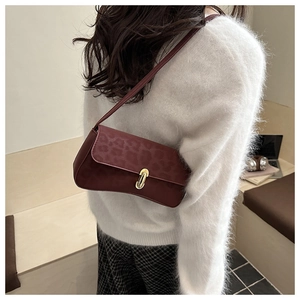 Close-up of a burgundy leopard embossed underarm bag with gold metal clasp on a model