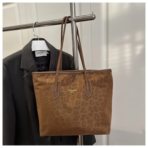 Detail of leopard print suede tote bag with golden logo and brown leather handles