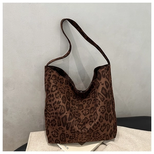 Detailed view of brown leopard print faux suede tote bag resting on a fashion magazine