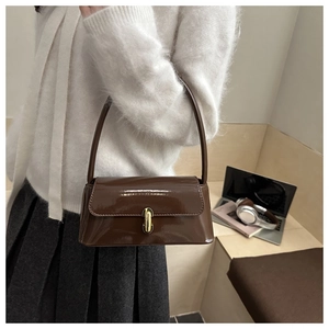 Close-up of brown glossy patent leather bag featuring a gold metal buckle and sleek handle