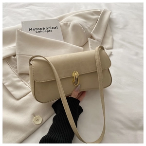 Close-up of beige baguette bag with a sleek golden rectangular clasp and slim shoulder strap