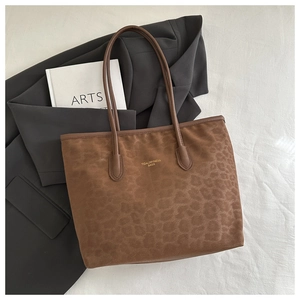 Detail of the leopard print texture and gold lettering on the brown suede tote bag