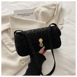 Detail of leopard print texture and gold metal clasp on black baguette shoulder bag