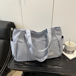 Borsa tote in tela azzurra con tasche anteriori ed etichetta su tavolo in legno