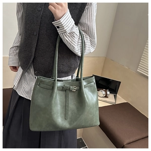 Deep green textured leather tote bag shown with laptop and books in a lifestyle setting