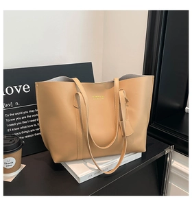 Close-up of light brown faux leather tote bag with elegant gold embossed fashion logo