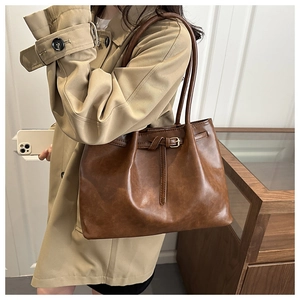 Detail of dark brown leather tote bag showing fine stitching and gold buckle accents