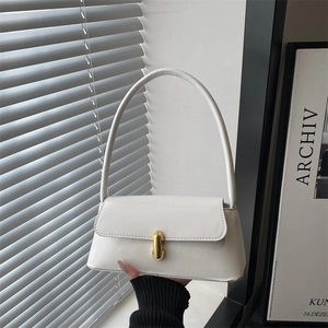 Minimalist white patent leather underarm bag with gold clasp shown in a modern lifestyle setting