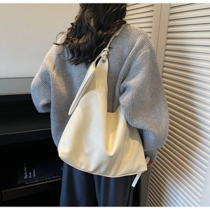 Detail of minimalist cream-colored large capacity hobo shoulder bag with knot strap detail