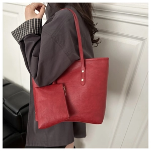 Detail of red faux leather tote bag set with metal rivets and matching small pouch