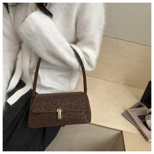 Detail of leopard print suede shoulder bag featuring a gold capsule shaped metal clasp