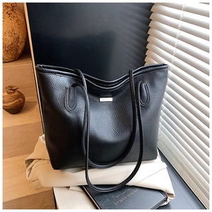 Gros plan d'un cabas en cuir grainé noir avec logo métallique et design minimaliste