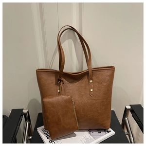 Detail of a brown leather tote bag with matching zippered pouch and gold rivet accents