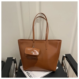 Close-up of a large brown tote bag with mini coin purse on a stylish modern chair