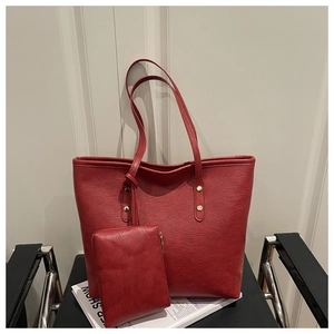 Close-up of red PU leather tote bag with grainy texture and golden rivet studs