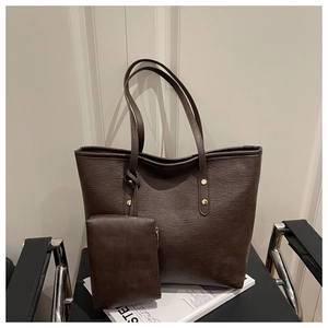 Detail of dark brown faux leather tote with matching pouch and gold rivet accents