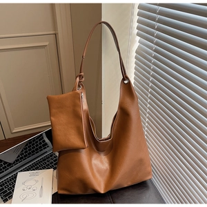Close-up of brown faux leather tote bag with matching coin pouch in a modern office setup