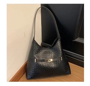Close-up of black woven leather texture and gold metallic buckle on commute shoulder bag