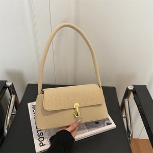 Beige leopard print shoulder bag with gold buckle on a black chair with magazine