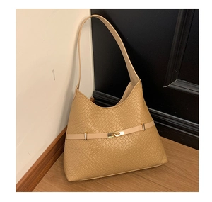 Detail of beige shoulder bag featuring woven texture and gold metallic twist lock closure