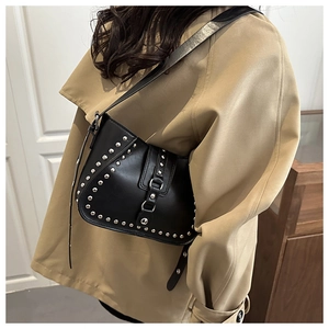 Close-up of black leather shoulder bag with vintage silver studs and adjustable strap