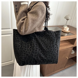 Close-up of a large leopard print tote bag styled with a brown blazer in a cozy room