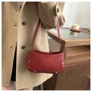 Detail of red crocodile texture PU leather shoulder bag with silver studs and heart patch