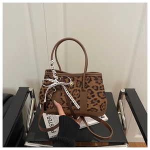 Détail du sac à main léopard avec poignées en cuir marron et un nœud décoratif en dentelle