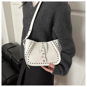 Detail view of a white saddle bag featuring silver rivet studs and a metal buckle strap