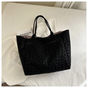 Detail view of large leopard print tote bag with black handles and velvet texture