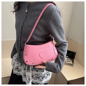 Detail of pink faux leather bag with heart texture and metallic rivet studs