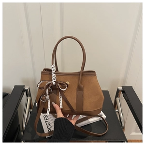 Détail du sac à main en daim marron avec garniture en cuir, fermoir et nœud en dentelle