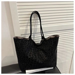Detail shot of a large leopard print tote bag with dual straps on a minimalist pedestal