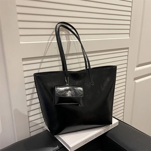 Glossy black large tote bag with matching coin purse on white decorative books