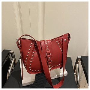 Detail of red leather shoulder bag featuring silver rivets and metal ring strap buckle