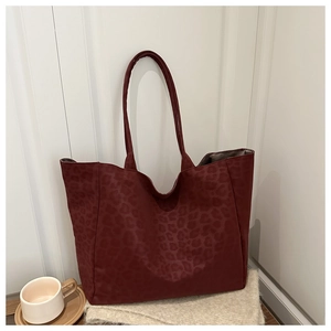 Detail view of burgundy leopard embossed texture on a large capacity tote bag