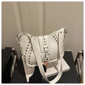 Macro detail of white leather shoulder bag featuring dense silver rivet studs and hobo style