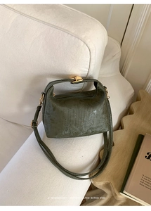 Macro detail of dark green textured leather surface and elegant gold metal twist lock