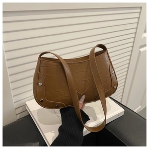 Detail view of brown crocodile texture shoulder bag with heart stitching and rivet accents